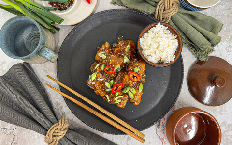 Glossy sauce-coated sweetbreads with a crispy coating, garnished with spring onions and red chilli