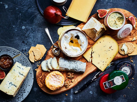 A wooden platter of artisan cheese, crackers and figs
