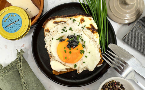 Golden yolked egg on top of an oozing croque madame with black caviar
