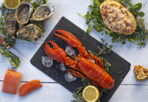 Whole lobster on a slate with ice cubes, oysters & a dressed crab